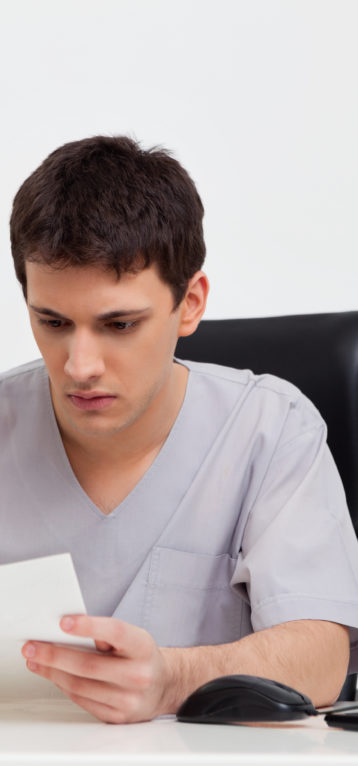 Serious male doctor reading reports of patient
